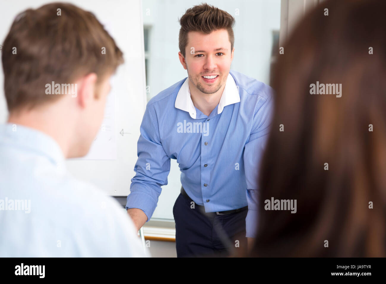 Businessman Smiling While Looking At Colleagues In Office Stock Photo