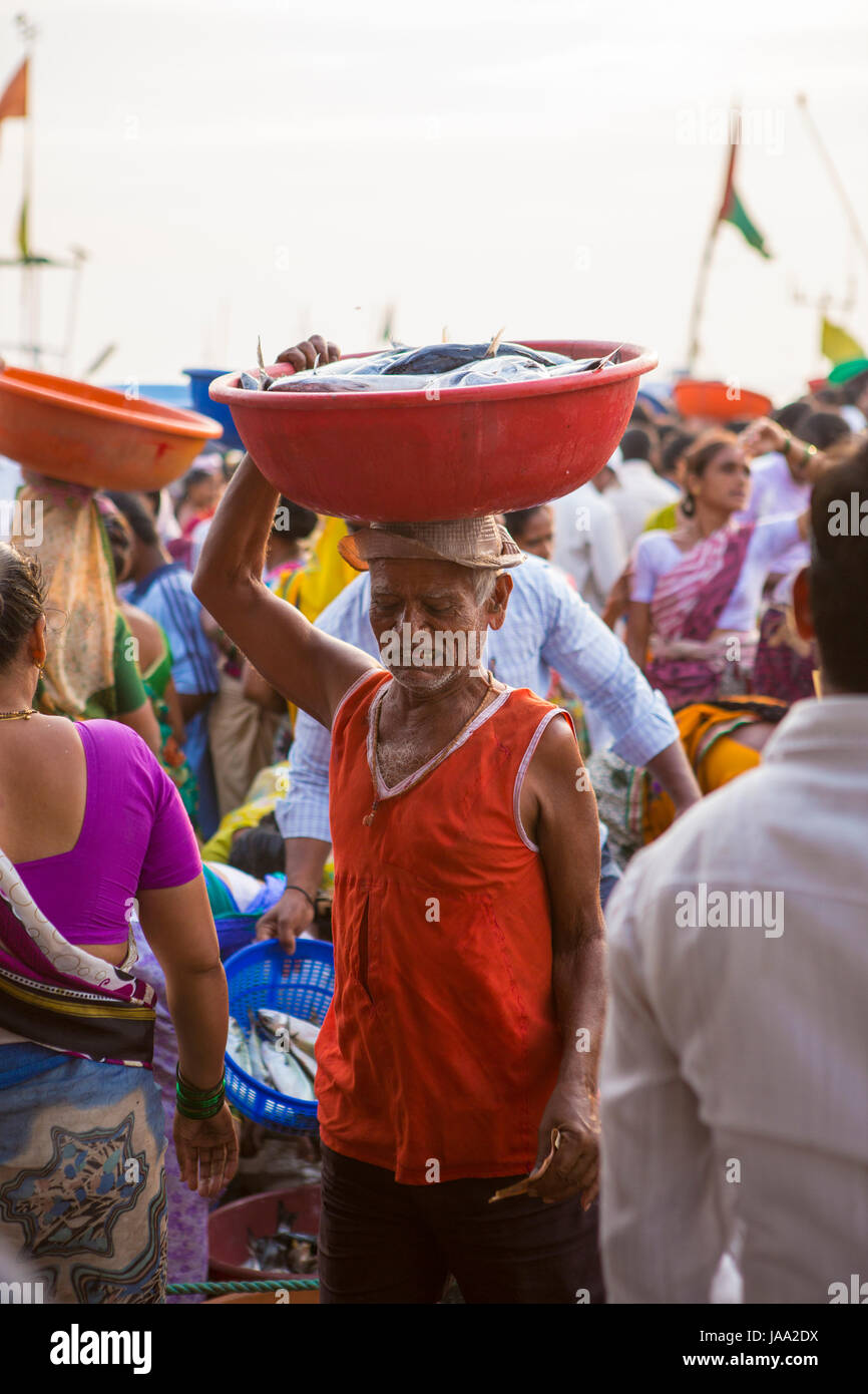 A man carries a bowl of fresh fish on his head, Sassoon fish market