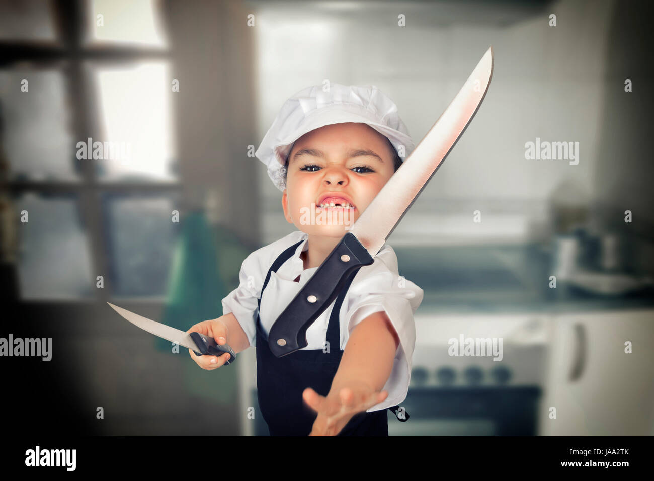 Funny portrait of a six years girl dressed as a cook throwing a knife