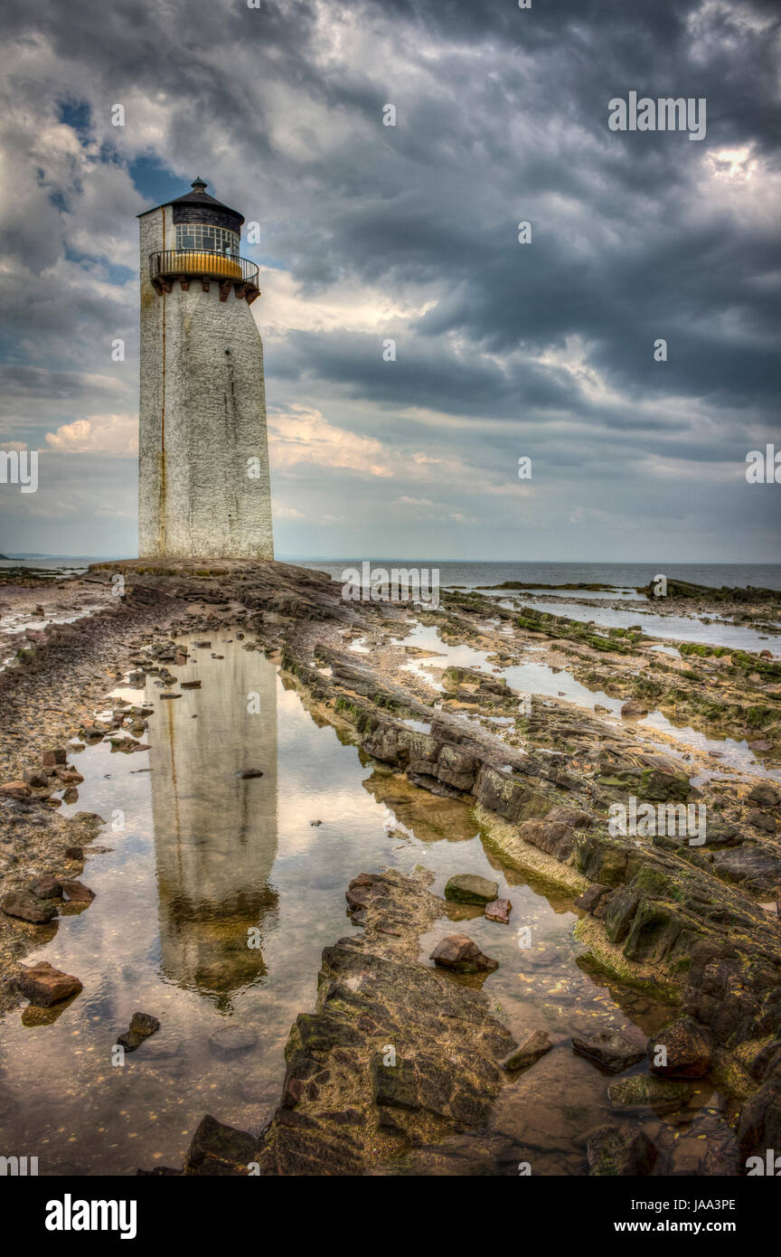 Storm approaching Southerness Lighthouse (reflected in rockpool), Dumfries and Galloway, Scotland. High dynamic range image. Stock Photo