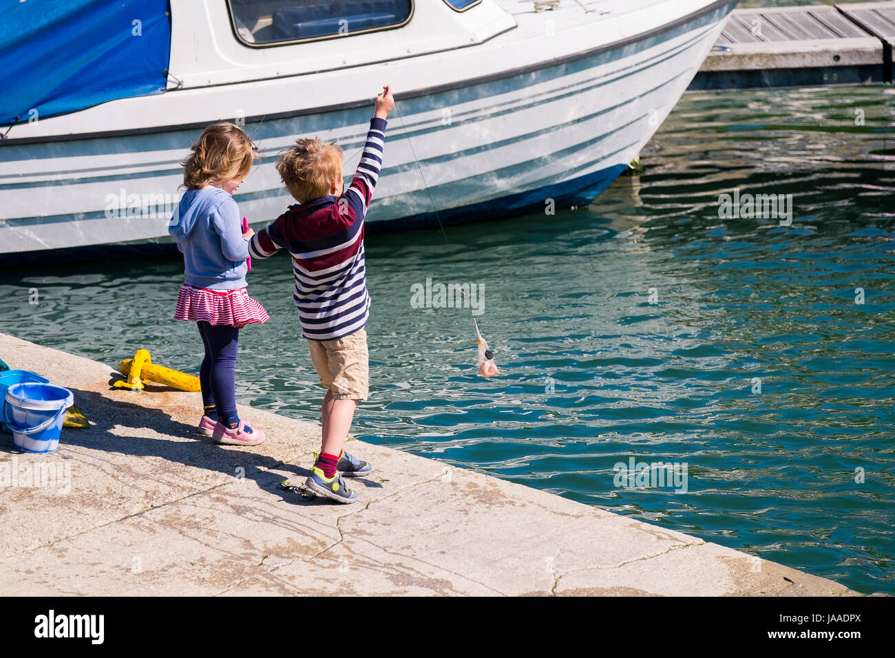 Two children crabbing in Padstow Harbour in Cornwall. Stock Photo