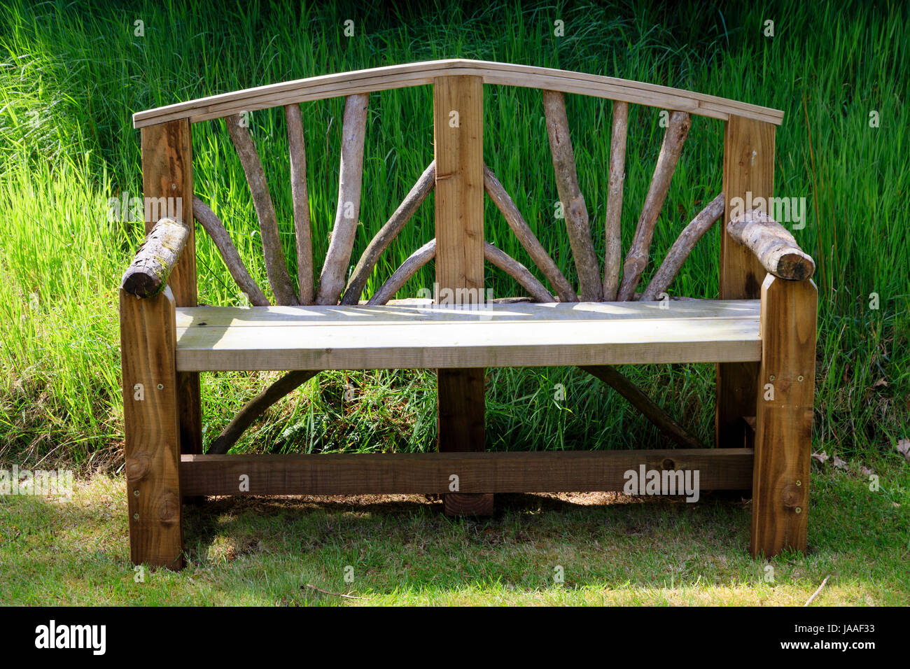 Rustic wooden bench combining rough logs and planed wood in a Devon garden Stock Photo