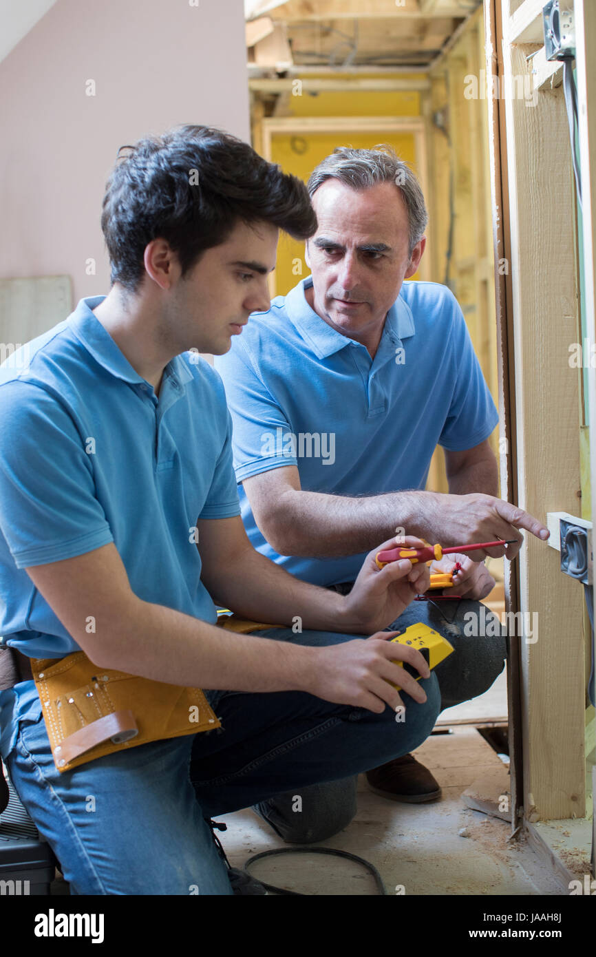 Electrician With Apprentice Working In New Home Stock Photo