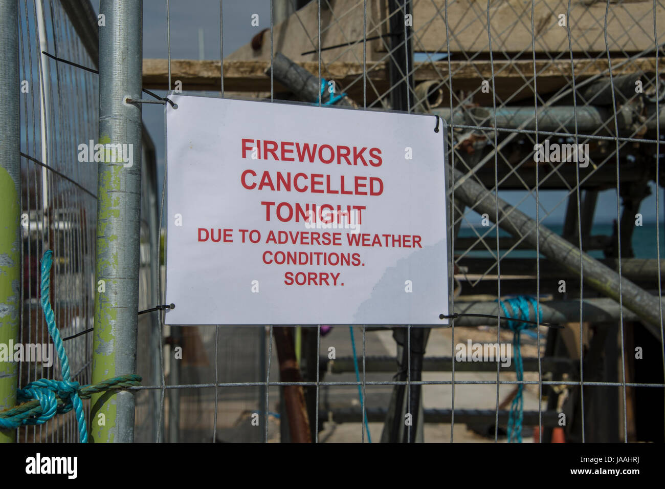 sign on a fence, firework display cancelled tonight due to adverse weather conditions, sorry. Stock Photo