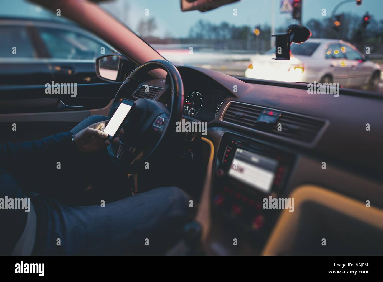 Texting While Driving Concept. Browsing Internet and Social Media While Behind the Wheel. Caucasian Men Texting During Car Drive. Stock Photo