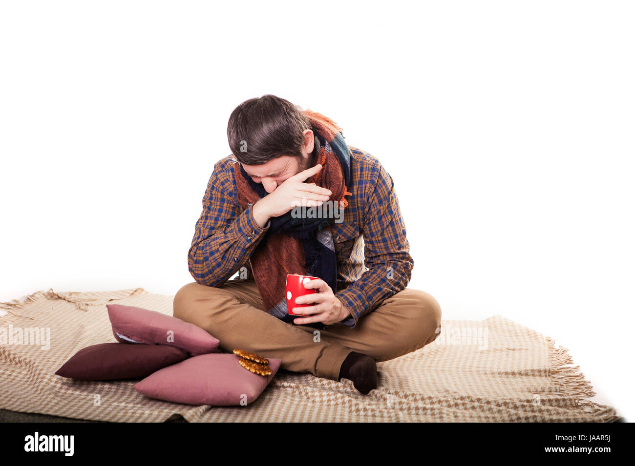 ill man with flu drinking tea and coughing at home. Stock Photo