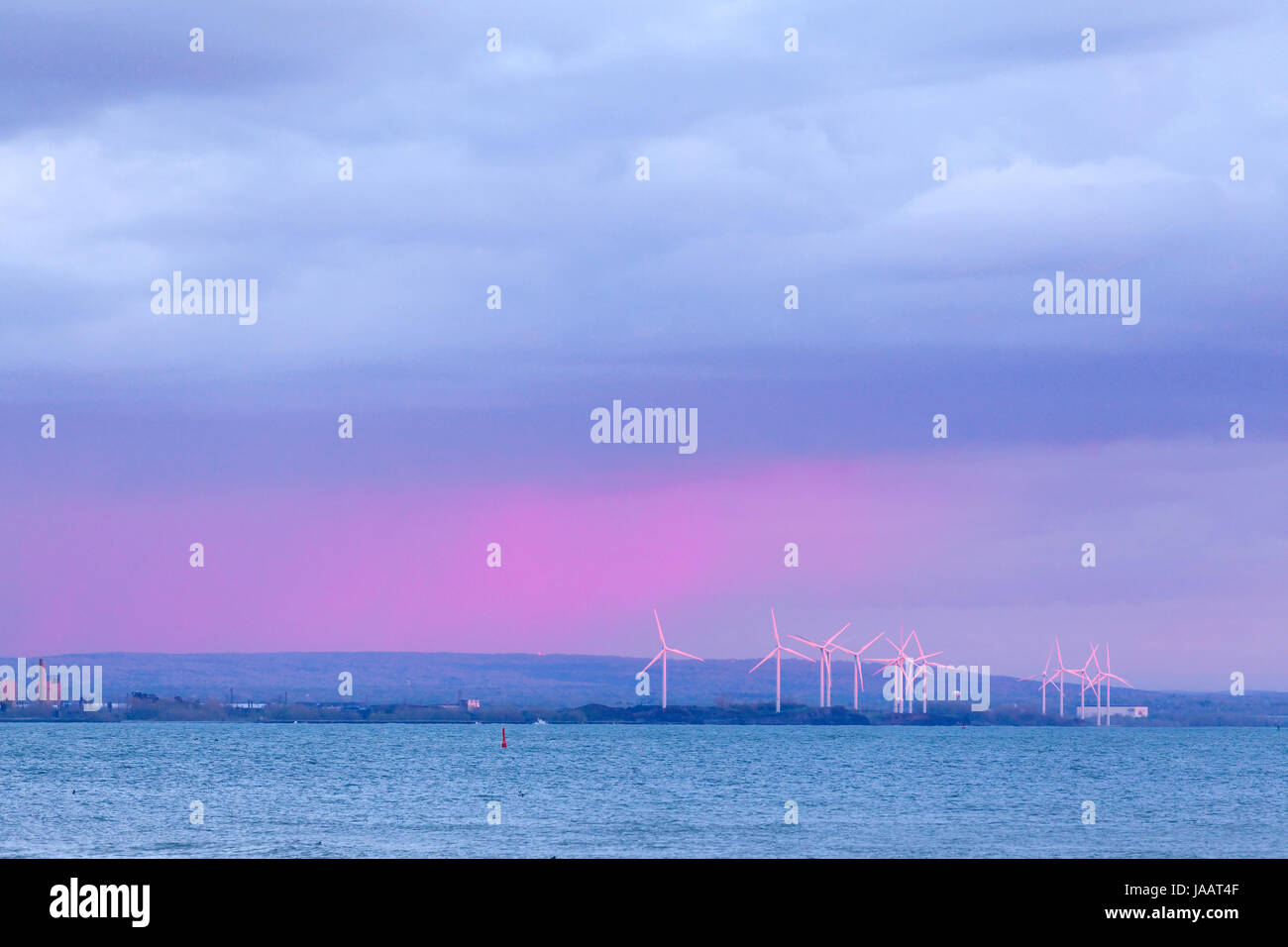 Wind turbines make up a Wind Farm on the Lake Erie shoreline during a colourful sunset. Buffalo, New York, USA. Stock Photo