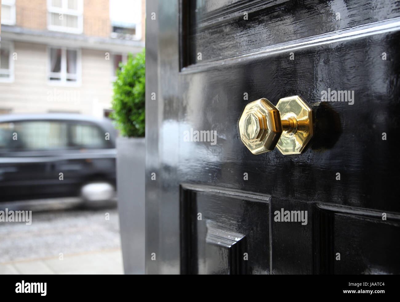 A typically British brass door knob on a front door on a central London street, UK. A London taxi passes. Stock Photo