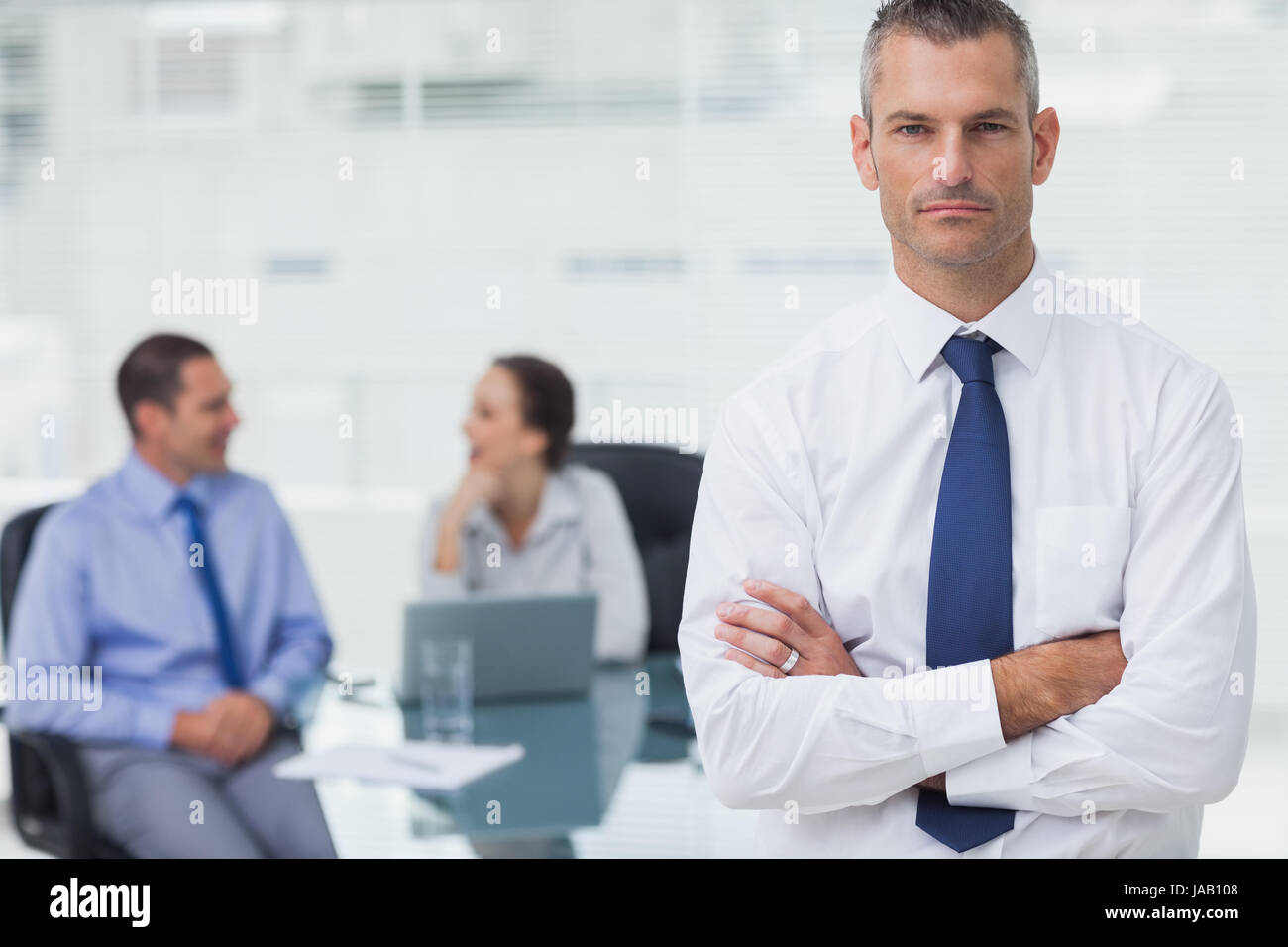Serious businessman posing crossing arms in bright office Stock Photo ...