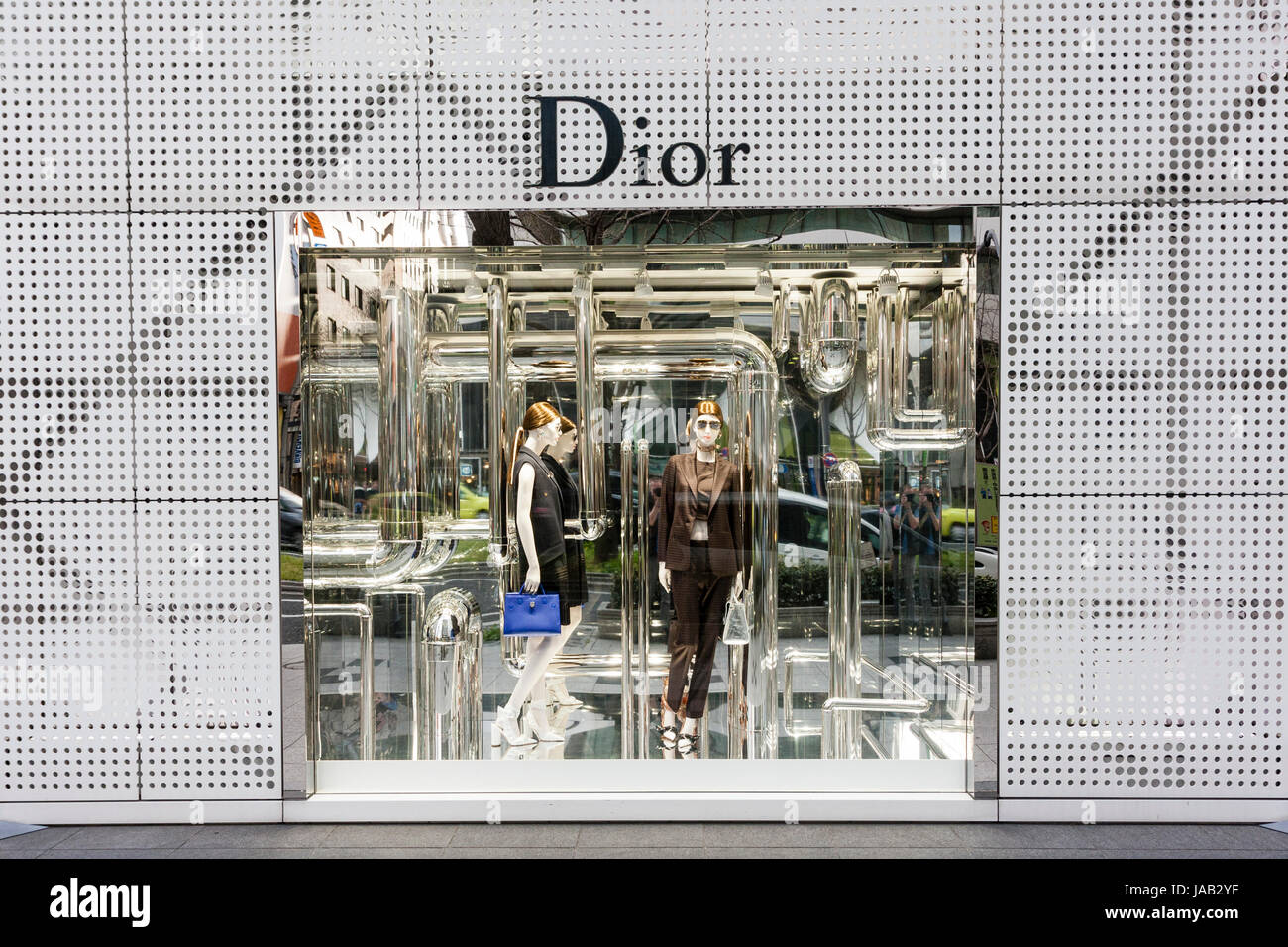 Japan, Osaka, Shinsaibashi. Dior fashion store shop window with dress display surrounded by grey grill patterned wall, with name above window. Stock Photo
