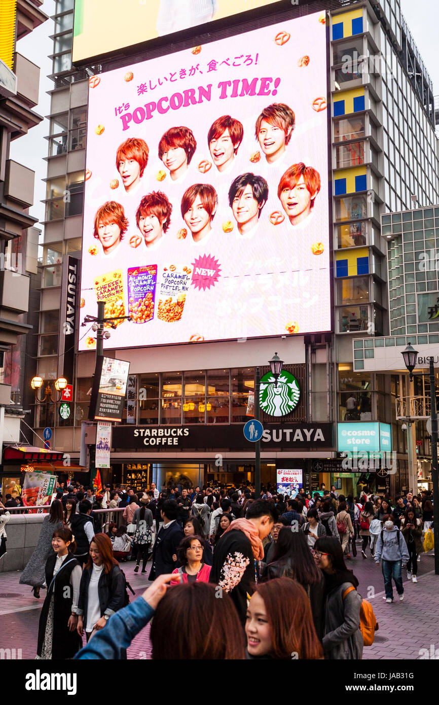 Dotonbori in Osaka. Crowded street at twilight evening time. Starbucks coffee shop with 4 storey high illuminated billboard sign for 'Popcorn time!' Stock Photo