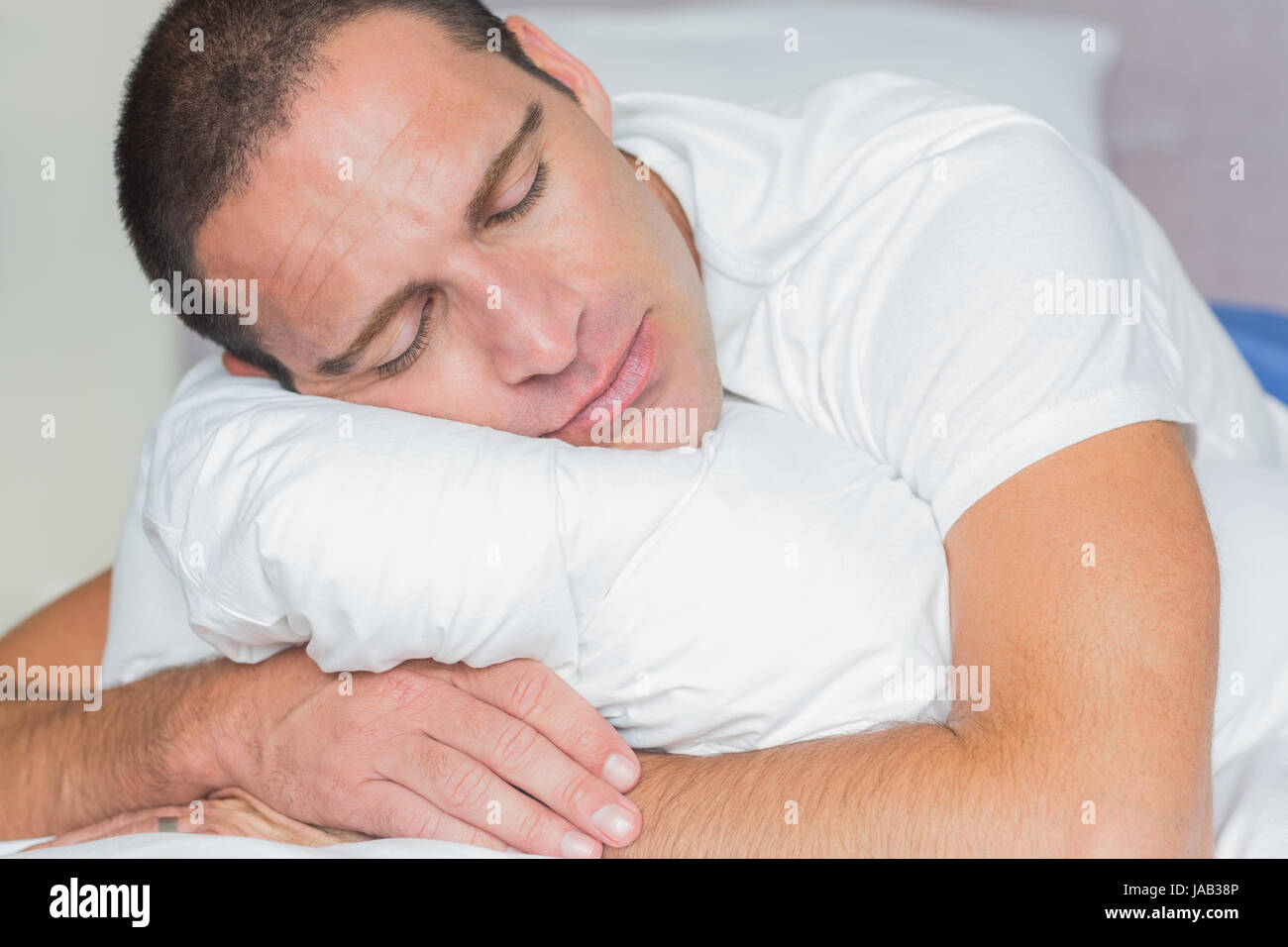 Sleeping Man Hugging His Pillow At Home In The Bedroom Stock Photo