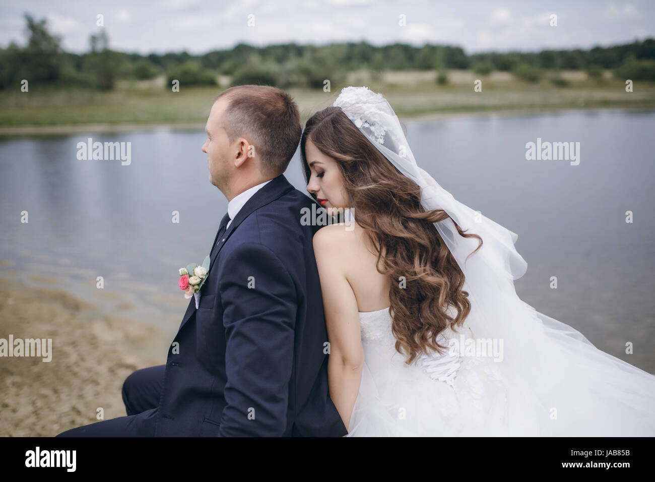 bride and groom sitting by the river Stock Photo - Alamy