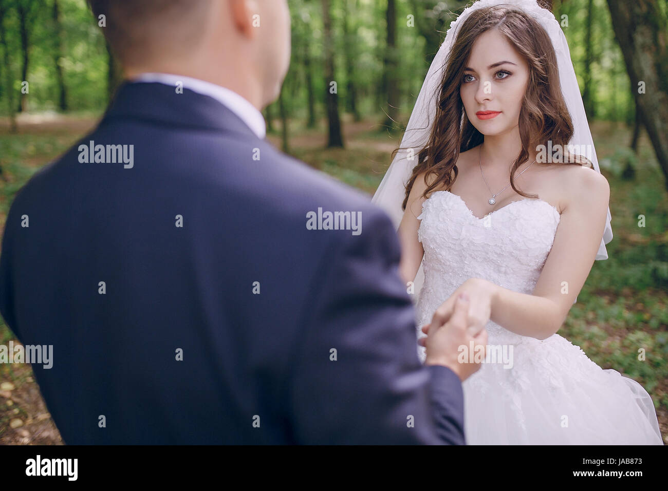 bride and groom walking in a green forest Stock Photo - Alamy