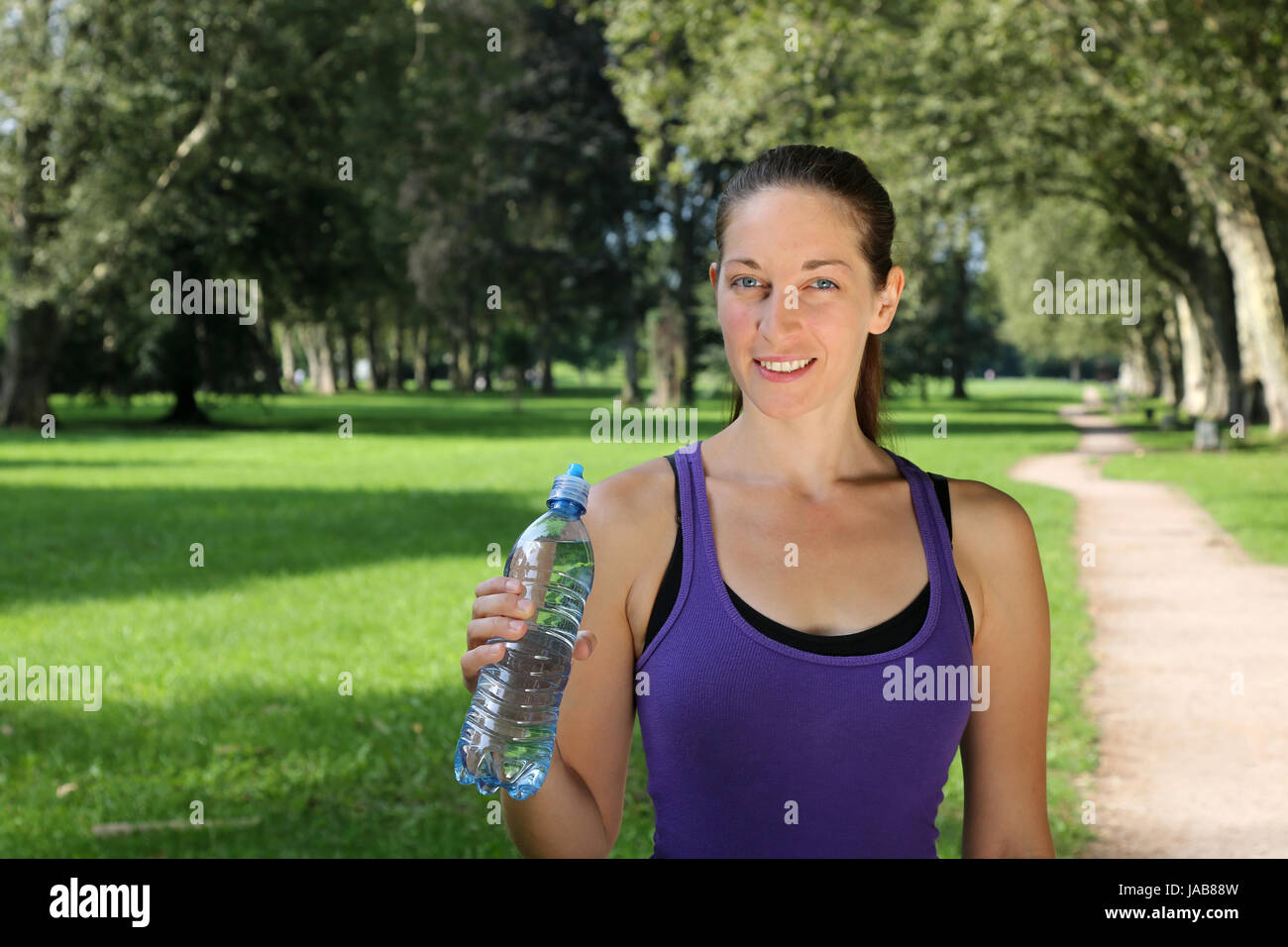Eine junge sportliche Frau mit einer Flasche Wasser beim Sport oder Laufen Stock Photo