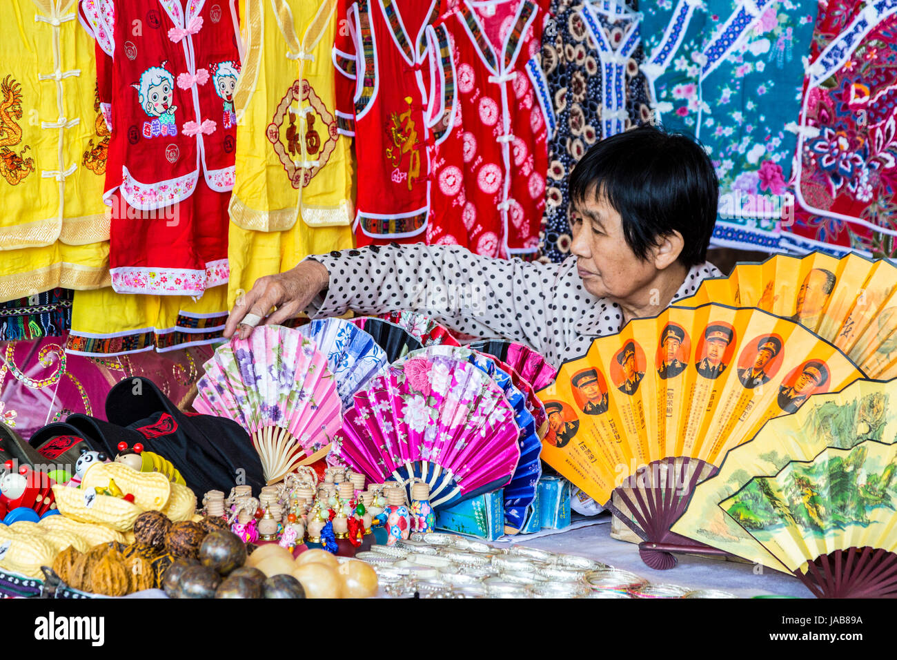 Yangshuo, China.  Vendor Selling Fans, Clothing, and Souvenirs. Stock Photo