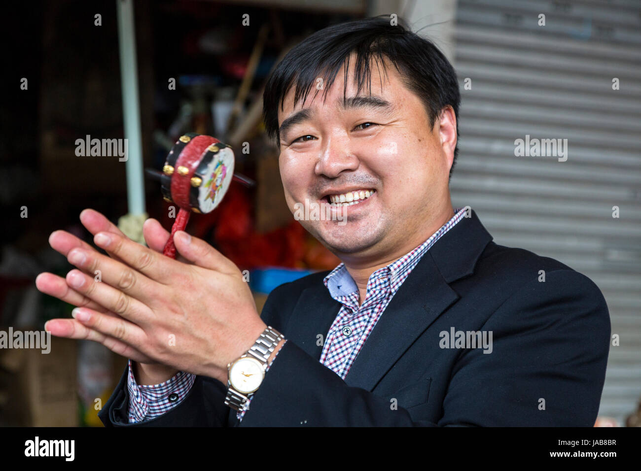 Yangshuo, China.  Vendor Rotating a Noise-rattle in his Hands. Stock Photo