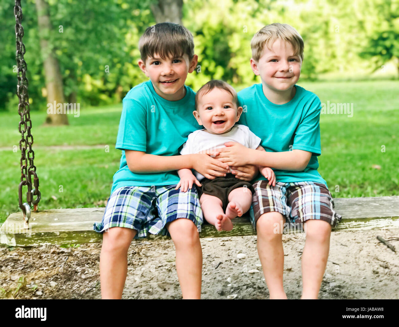 Three boys on a swing Stock Photo
