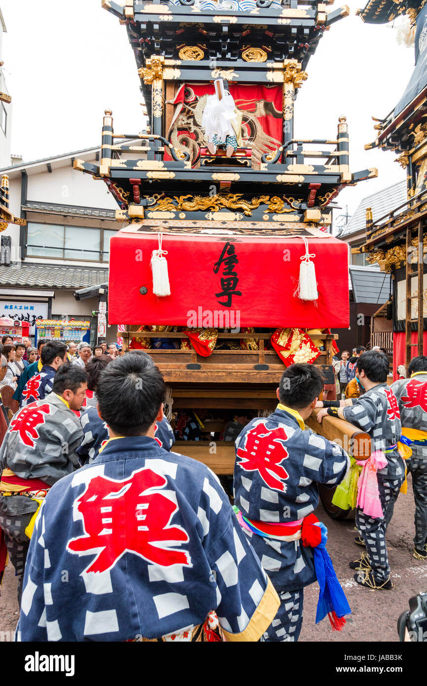 Inuyama festival in Japan, massive 3 storey wooden Dashi float, also called yatai or yama, being pushed through spectator crowded street Stock Photo