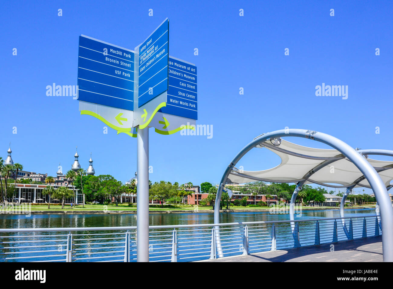 A blue directional information sign stands on Tampa Riverwalk on the Hillsborough River, overlooking the University of Tampa's campus in Tampa, FL Stock Photo
