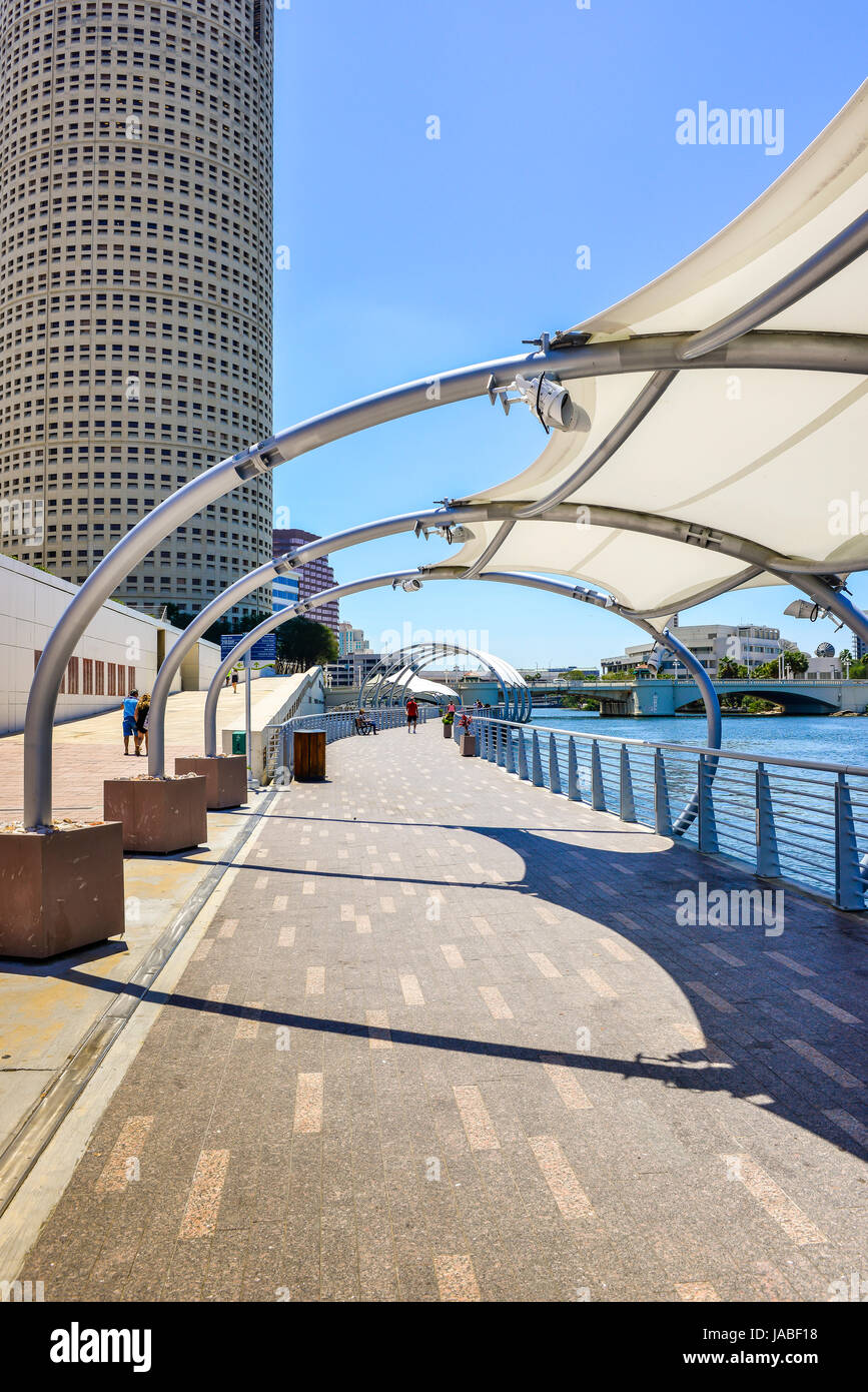 Pedestrians enjoy a stroll on the Tampa River Walk along the Hillsborough River with sunshade sails overhead with many nearby attractions in Tampa, FL Stock Photo