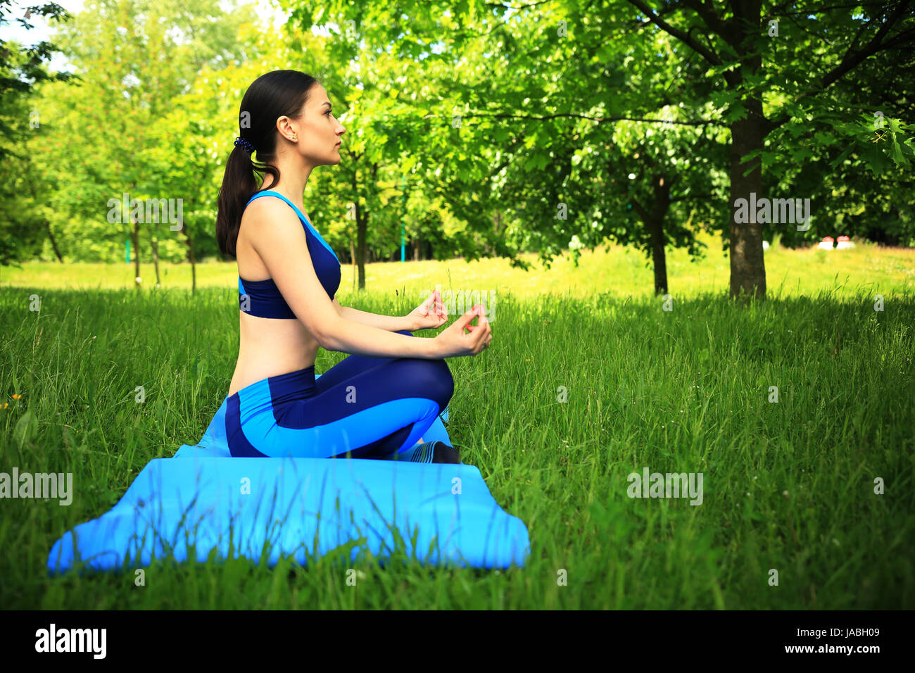 Fitness scene. Girl in lotos pose in park. Pretty girl doing yoga  outdoors. Stock Photo