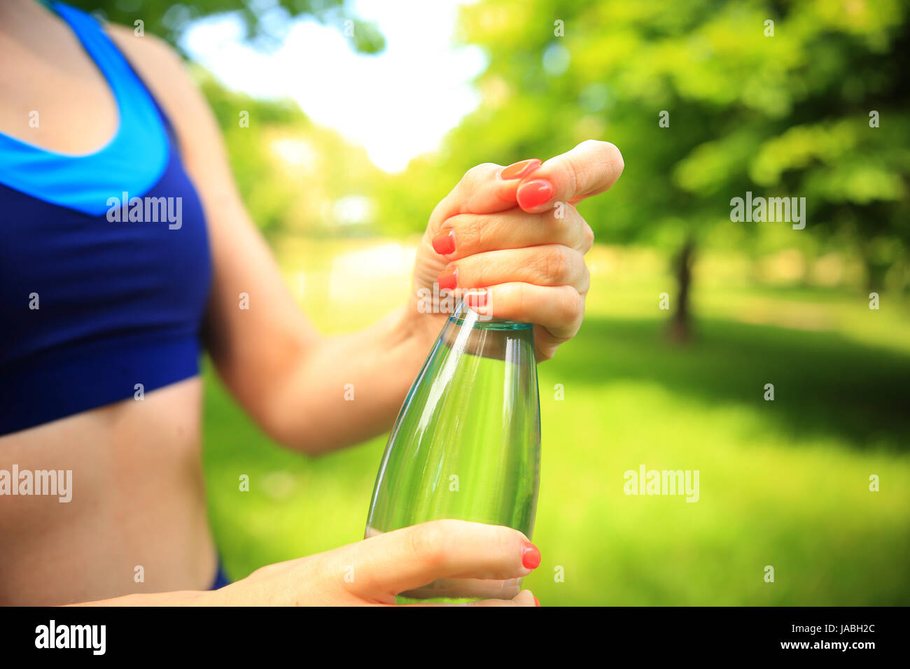 Healthy lifestyle theme. Opening bottle of water close-up. Girl opens bottle of water after fitness outdoors. Stock Photo