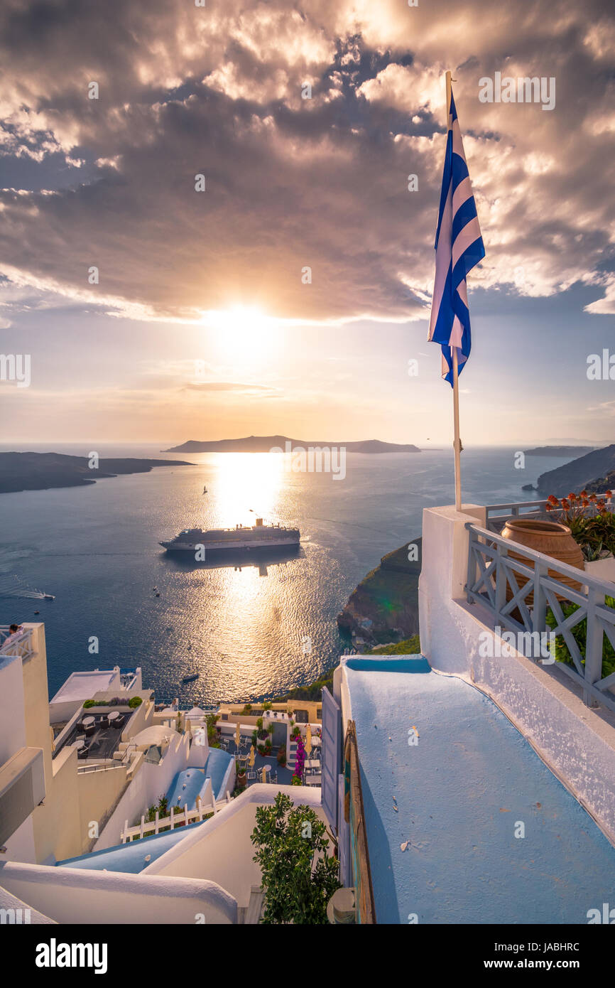Amazing evening view of Fira, caldera, volcano of Santorini, Greece with cruise ships at sunset. Cloudy dramatic sky. Stock Photo