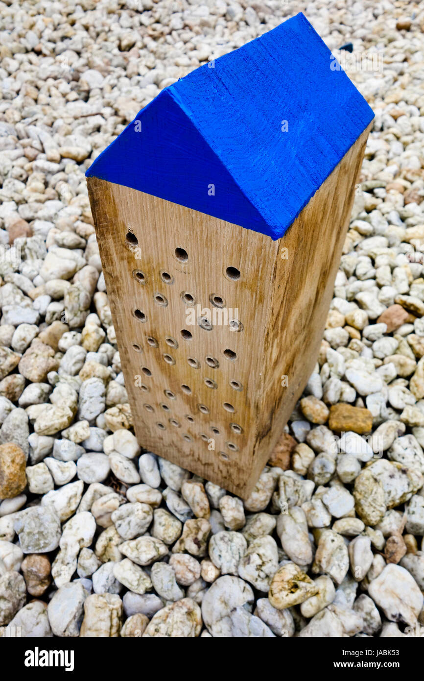 A decorative solitary bee house made from a solid oak wood block with blue roof Stock Photo