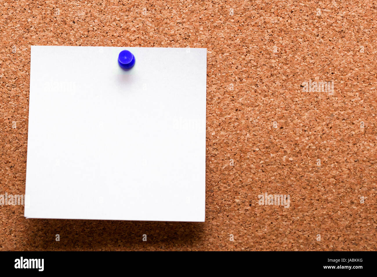 White paper with blue clip nailed on wooden board. Stock Photo