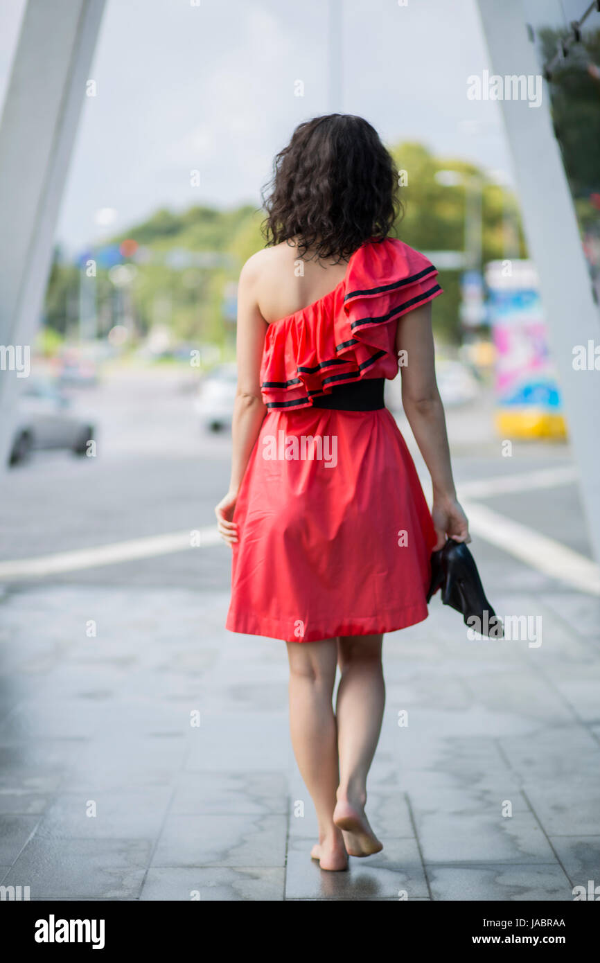 Woman in red dress walking barefoot on square Stock Photo - Alamy