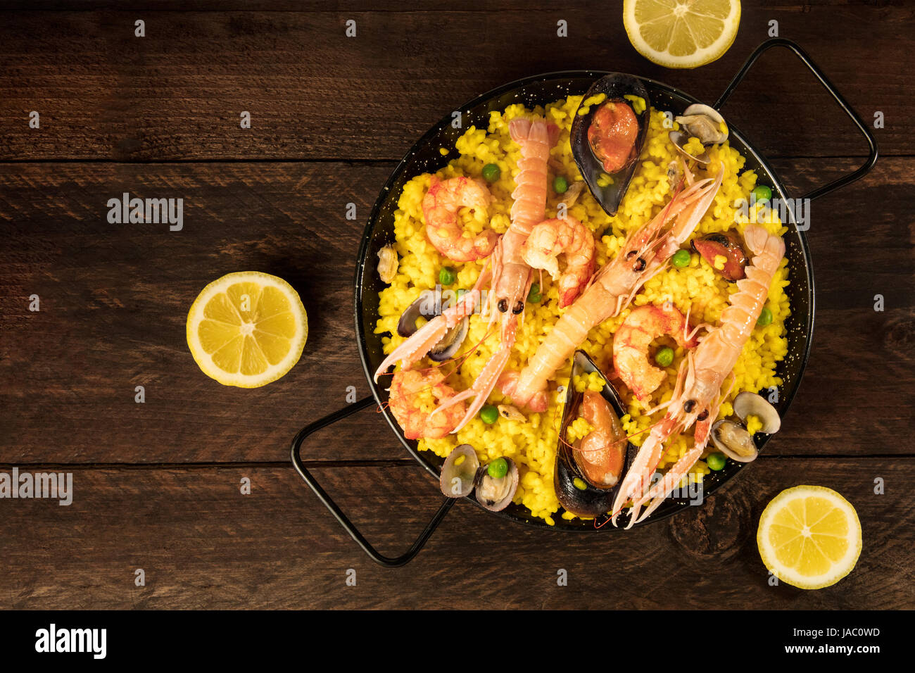 Spanish seafood paella in paellera, with lemons Stock Photo