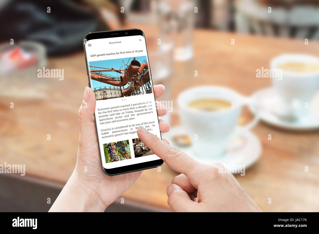 Read news article with smart phone. News portal web site with business information. Economic growth article. Coffee on table in background. Stock Photo