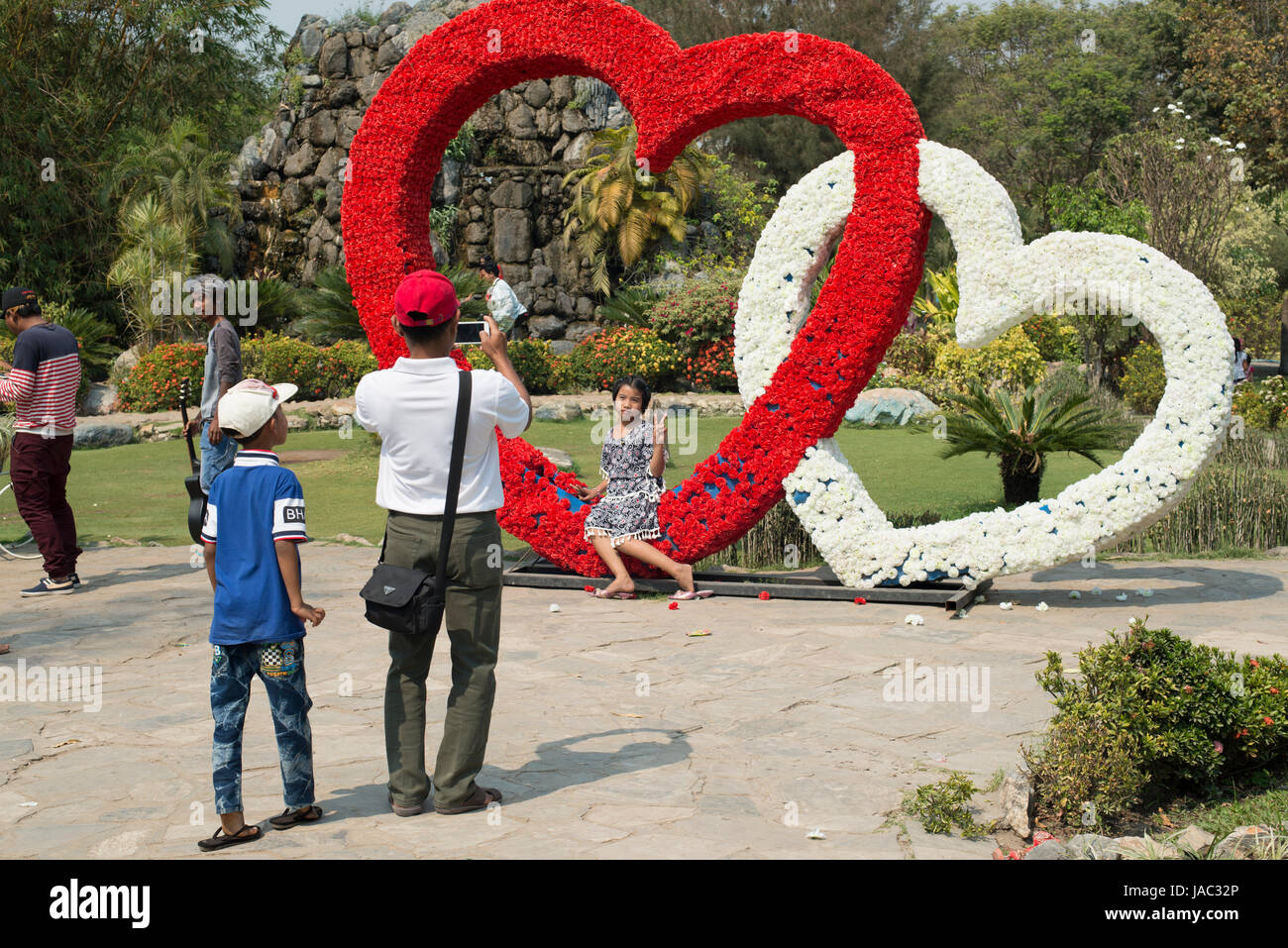 A father takes a photo of his daughter at a park in Mandalay, Myanmar (Burma) Stock Photo