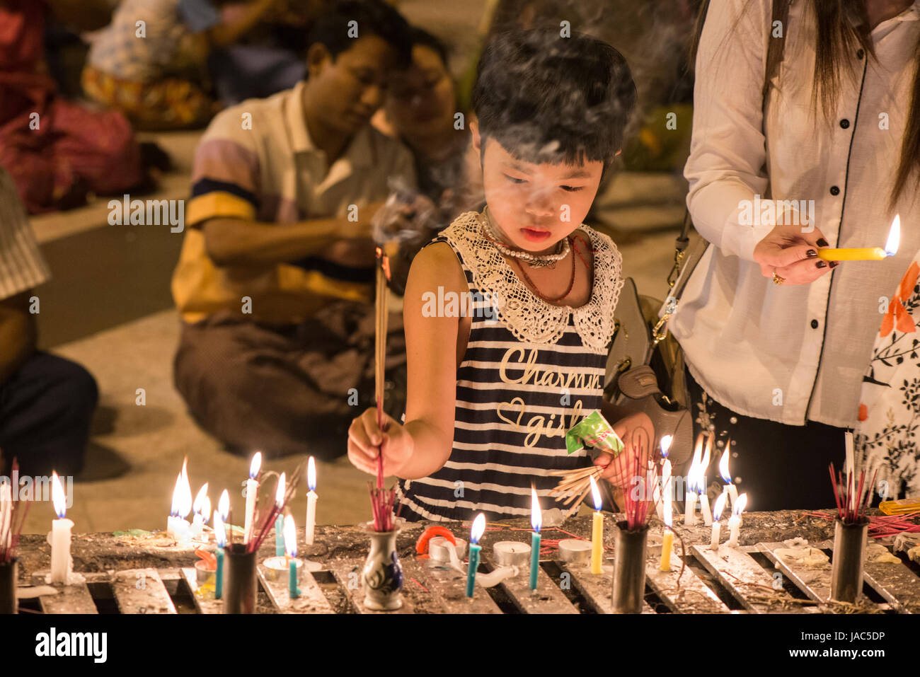 A young pilgrim lights a candle at a shrine at the Shwedagon Pagoda in Yangon (Rangoon), Myanmar (Burma) Stock Photo