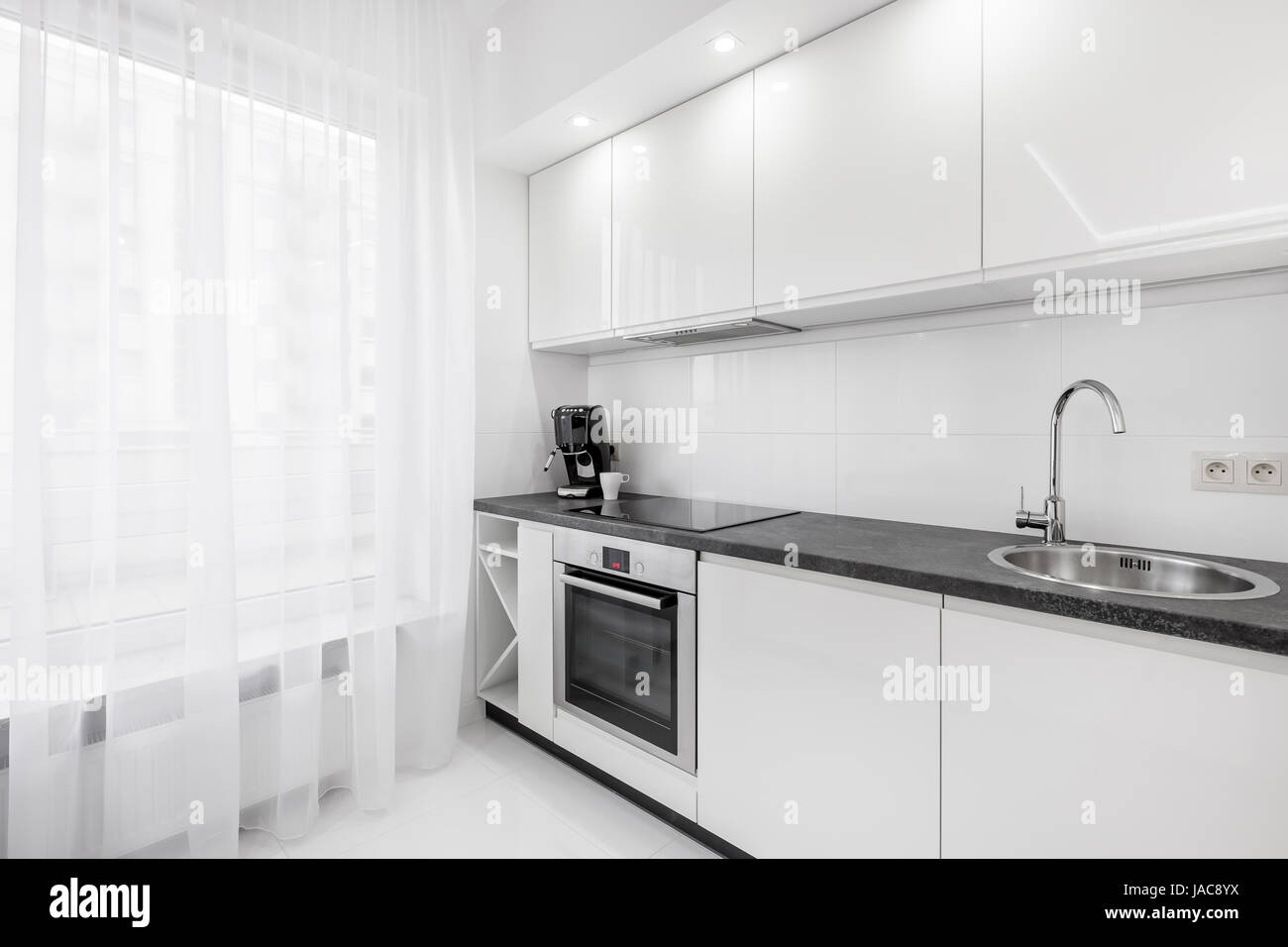 Modern White Kitchen With Black Countertop Sink Cupboards And