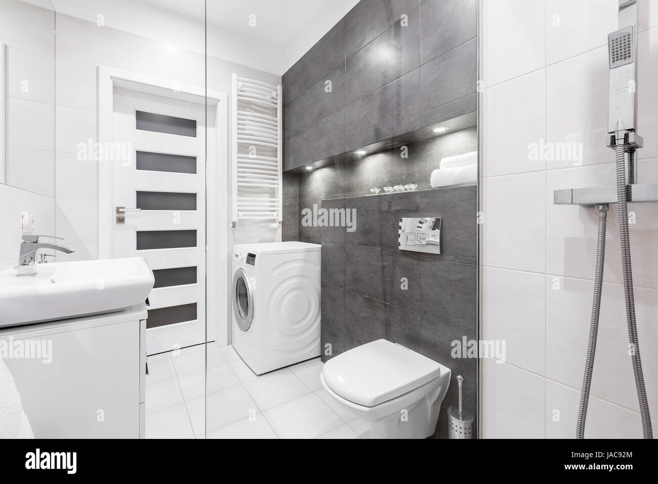 Modern, white bathroom with shower, sink, toilet, washer and gray wall Stock Photo