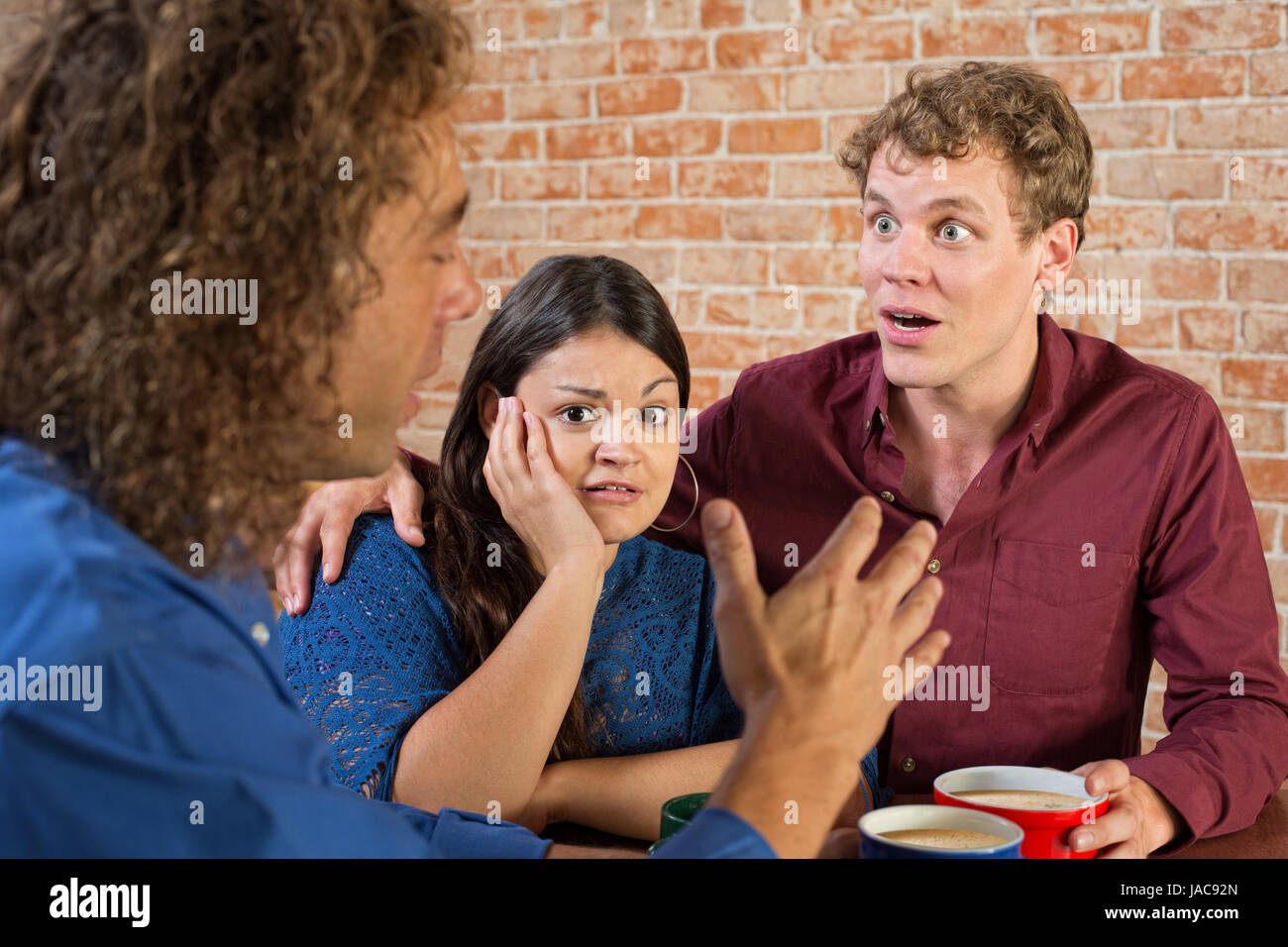 Shocked Hispanic woman listening to man talking Stock Photo - Alamy