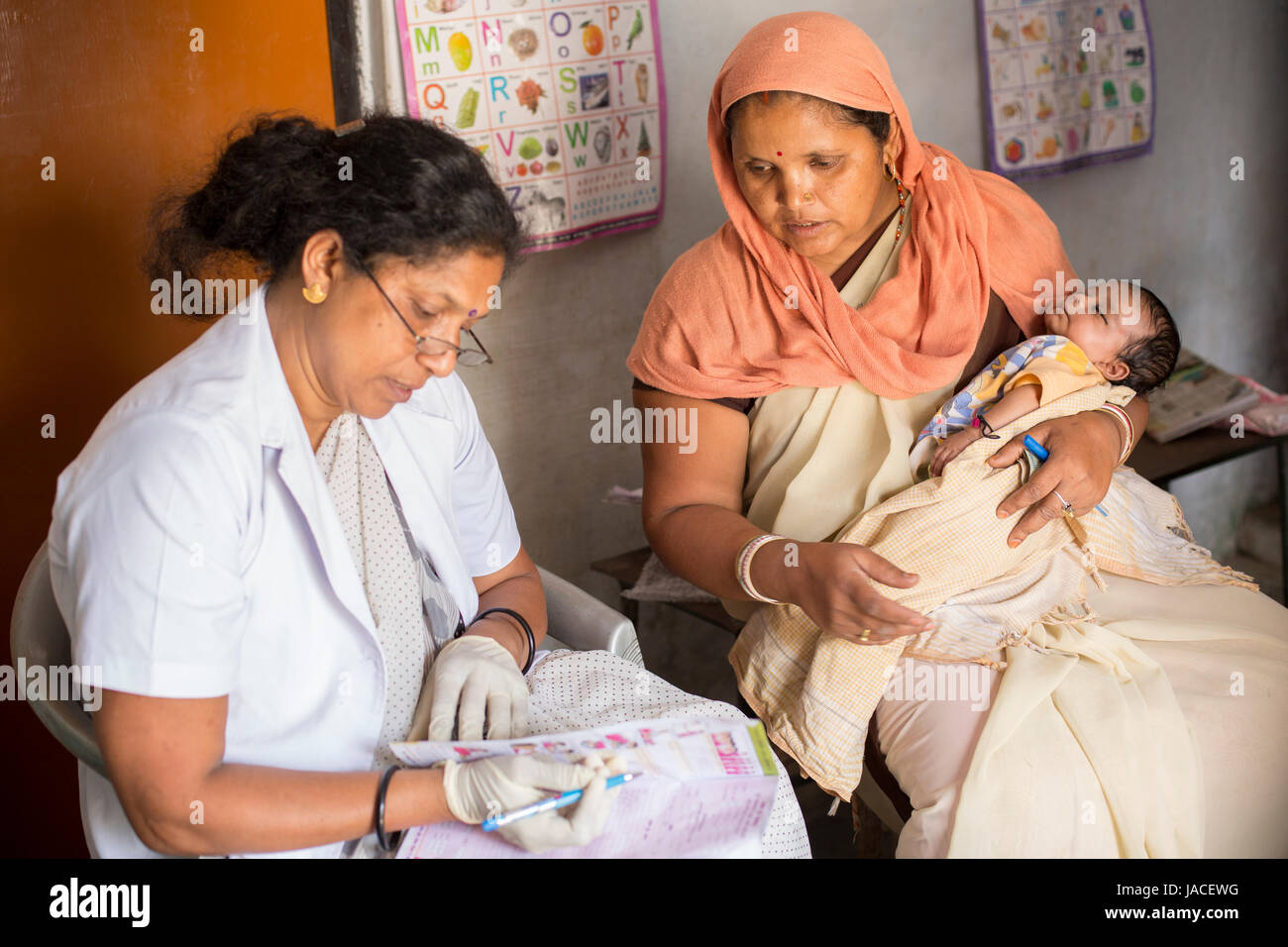 A mother brings her baby to a routine vaccination at a health centre in Uttar Pradesh, India. Stock Photo