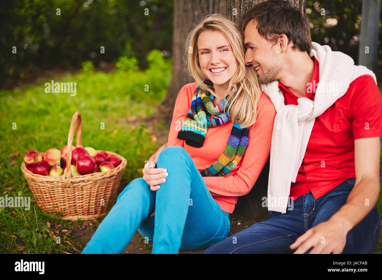 Happy young couple sitting in park and talking Stock Photo - Alamy