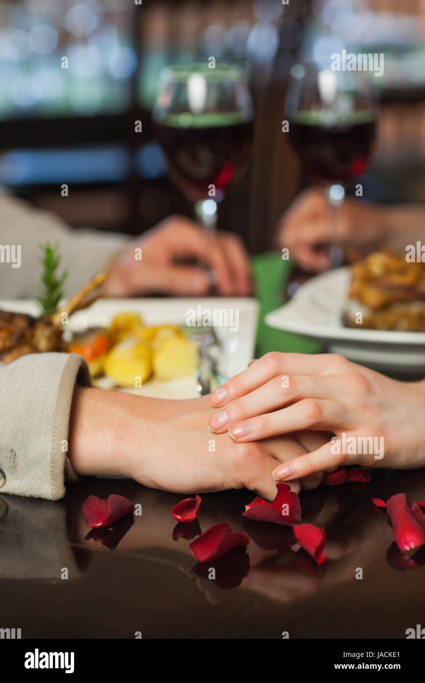 Close up on couple holding hands during dinner in a romantic restaurant Stock Photo