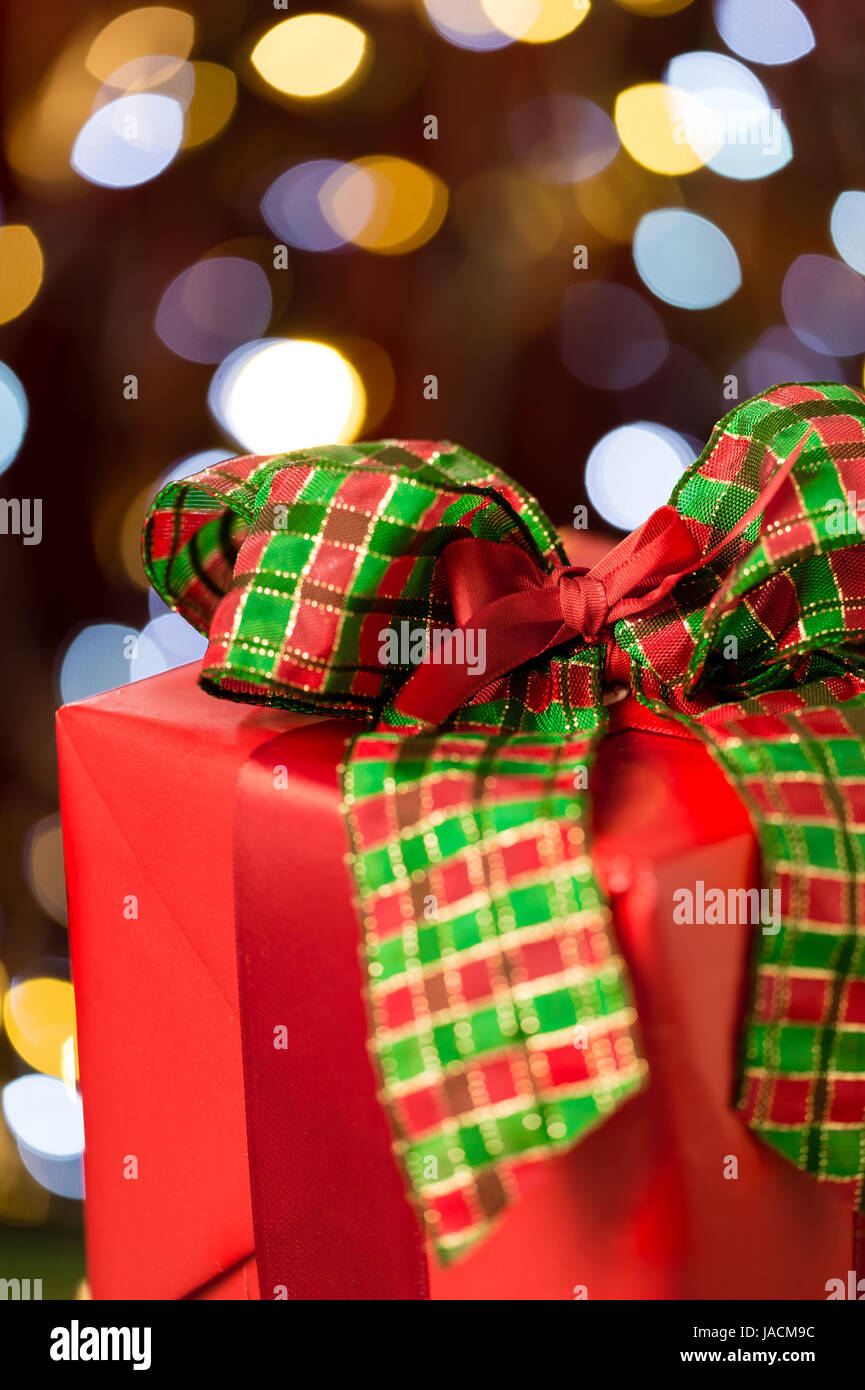 Traditional red christmas present with bow on shining lights background