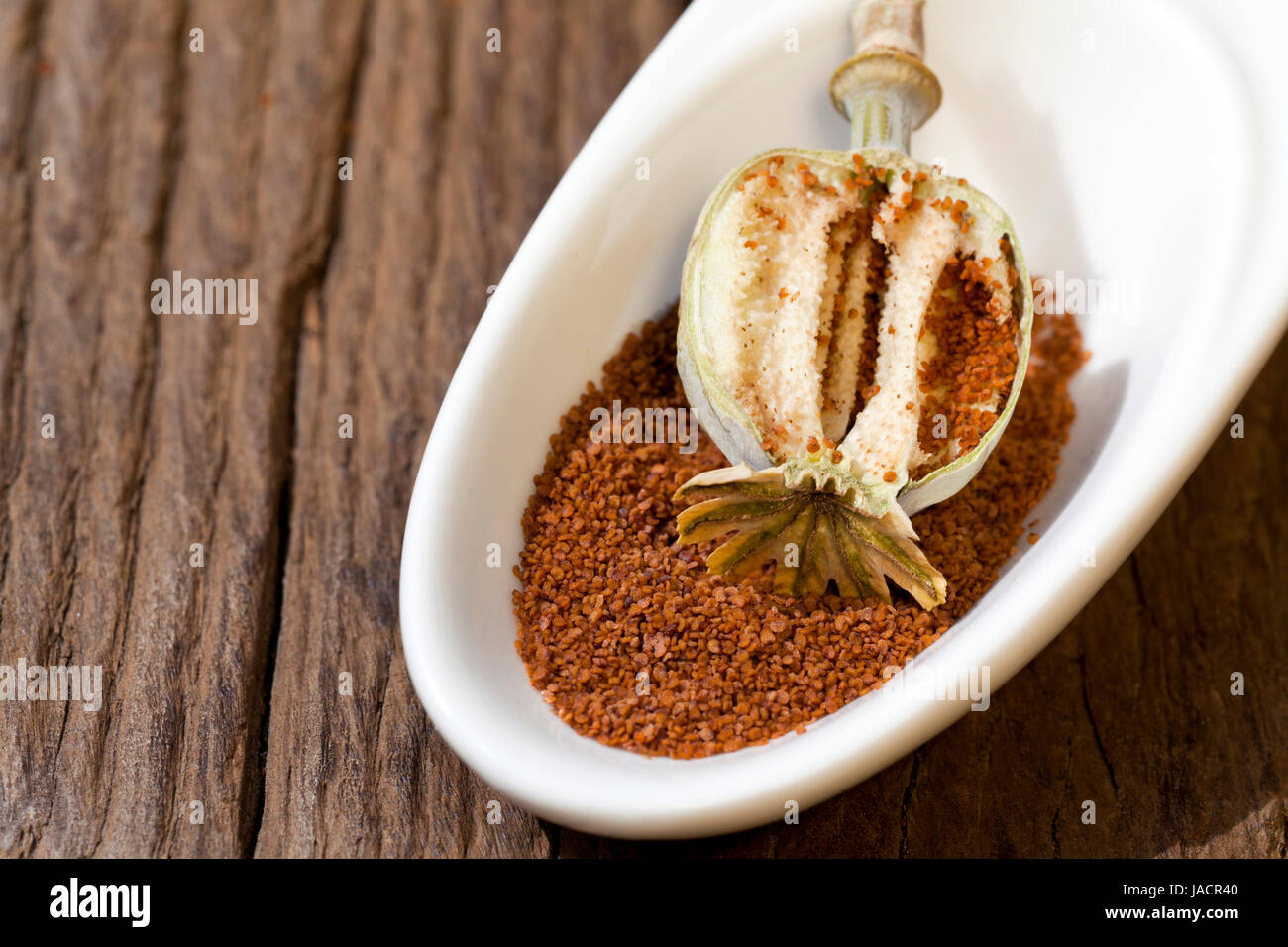 Aufgeschnittene Mohnkapsel liegt in einer Schale mit Mohnsamen Stock Photo