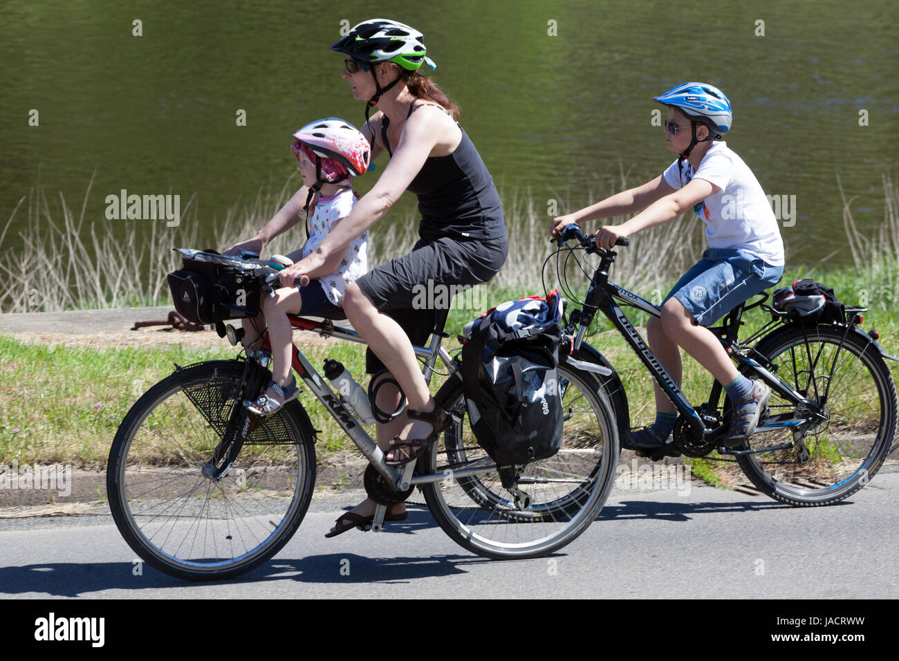Germany cycling family mother with two children, the toddler sitting in a child seat and everyone has helmets Elbe river bike Route Bike trail Child Stock Photo