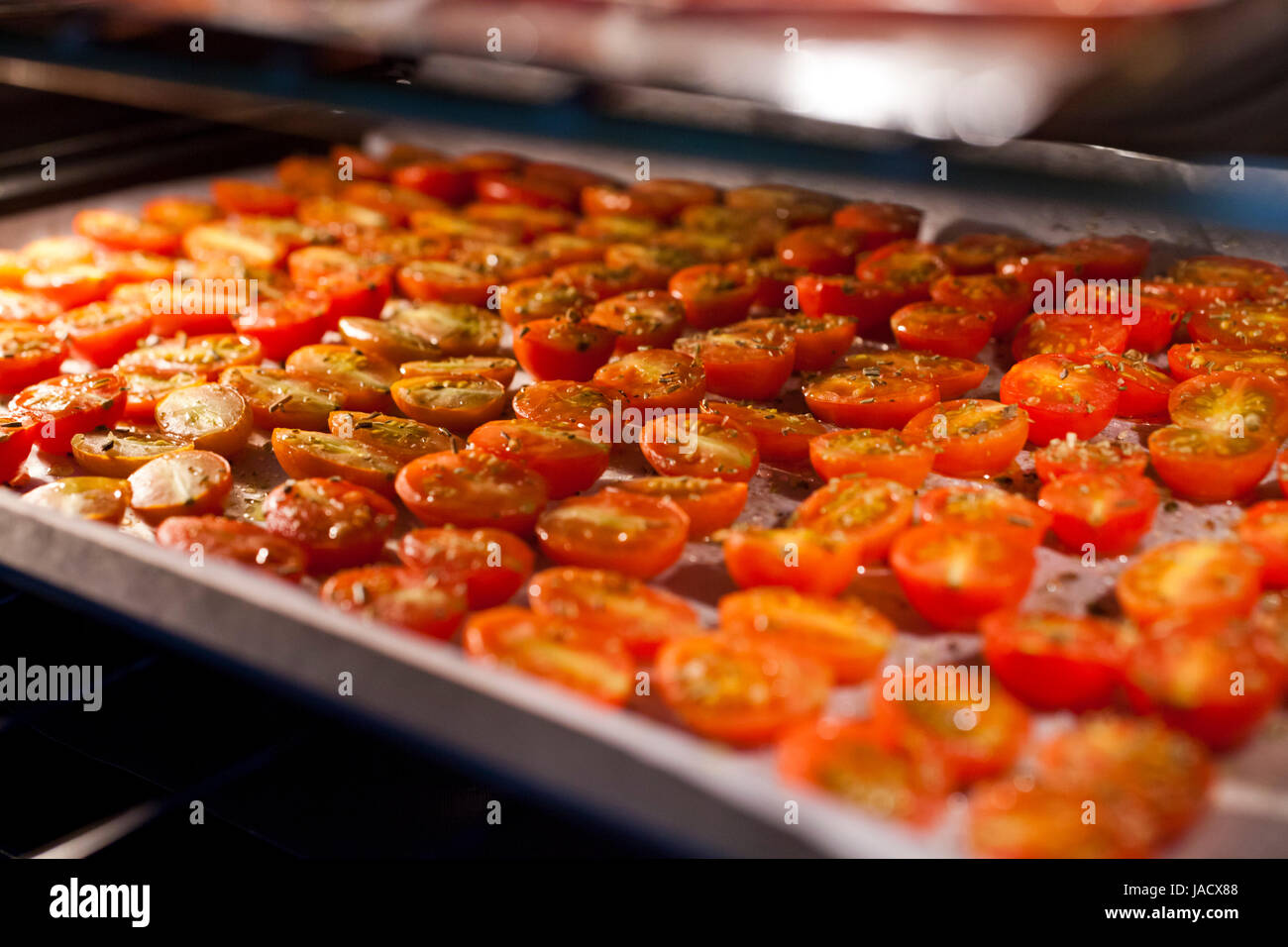 Trays of fresh cherry tomatoes on racks drying in the oven Stock Photo