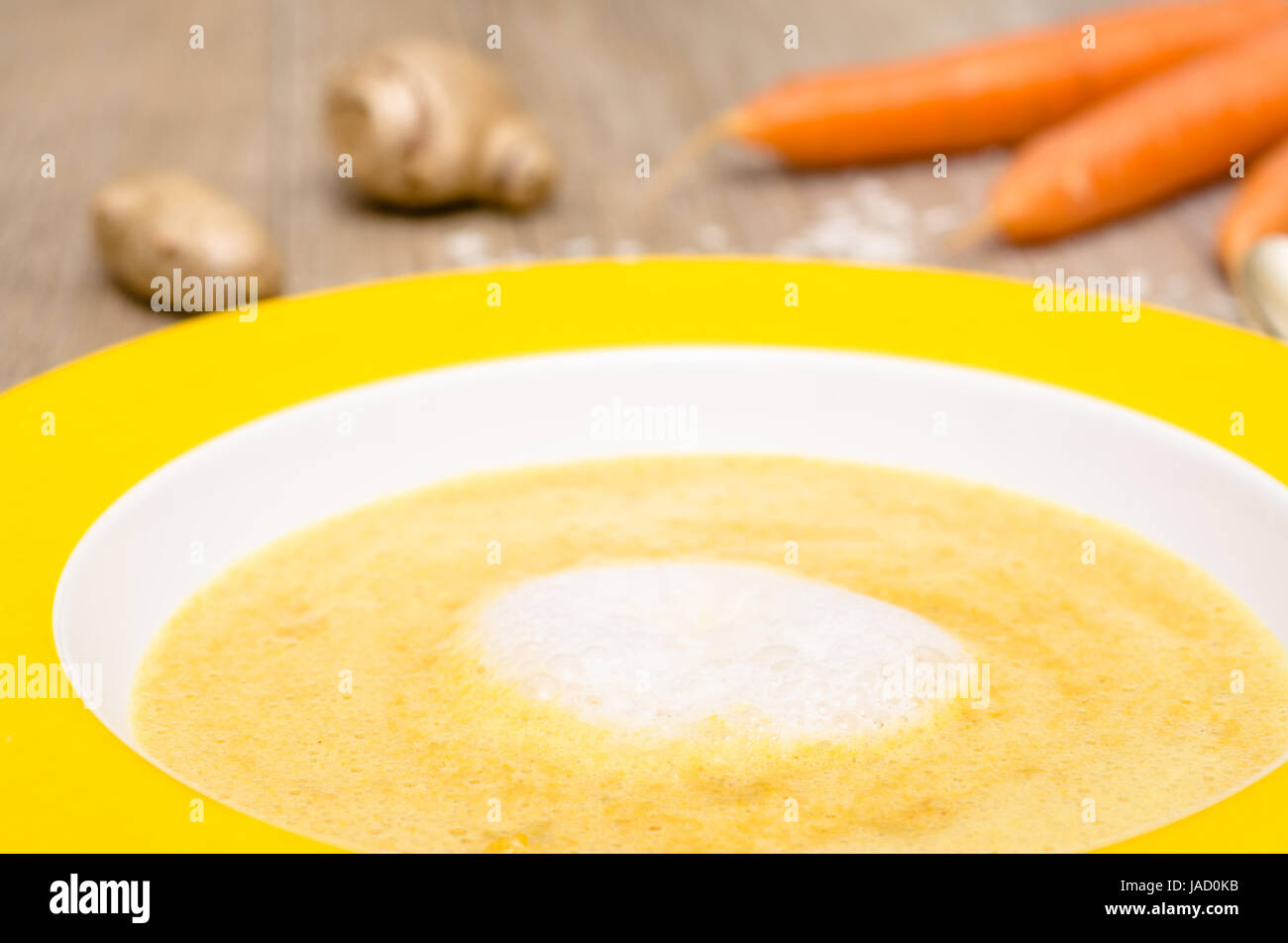 Schaum von Kokosmilch auf Suppe mit Karotten in einem Teller Stock Photo