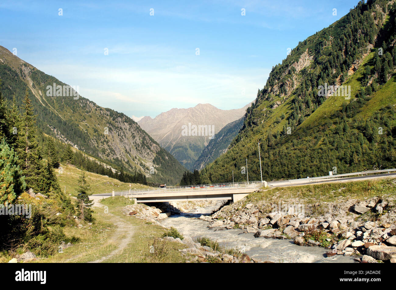 Brücke über einen Gletscherbach im Stubaital in Tirol, Oesterreich, steile Berge und grüne Hänge  Bridge over a glacial stream in the Stubai Valley in Tyrol, Austria, steep mountains and green slopes Stock Photo