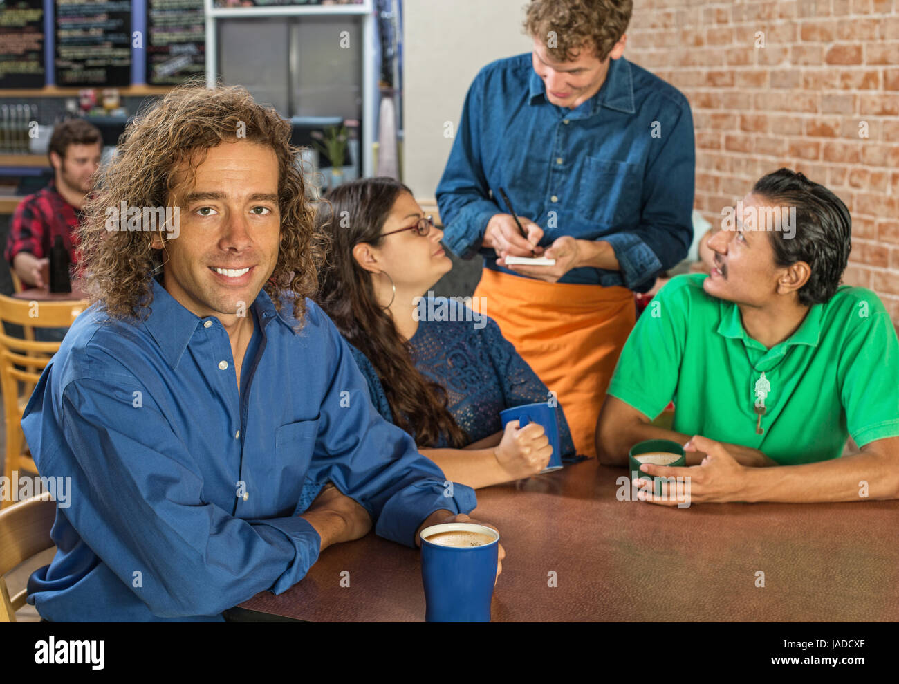 Grinning man with friends and barista at cafe Stock Photo