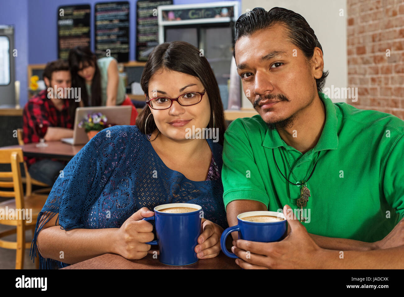 Grinning Latino and Asian couple in cafe Stock Photo