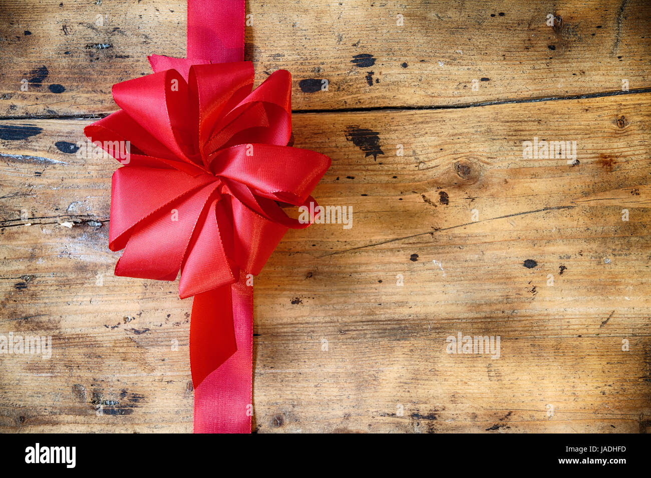 Decorative red ribbon and bow on a rustic wood background with ...